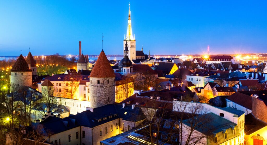 Night view of Tallinn, Estonia, showcasing its historic architecture and vibrant city lights against a dark sky.