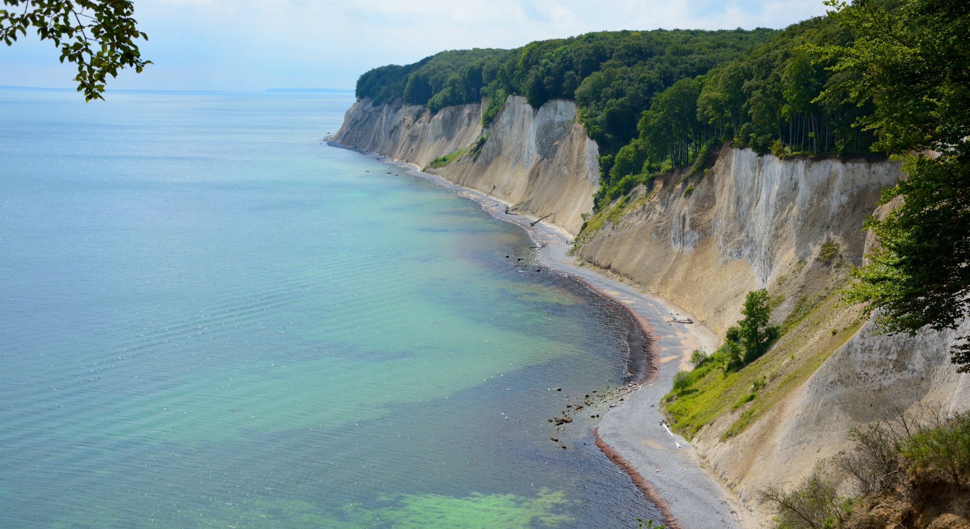 A scenic view of the Baltic Sea from a high cliff, showcasing the coastline and waves below.