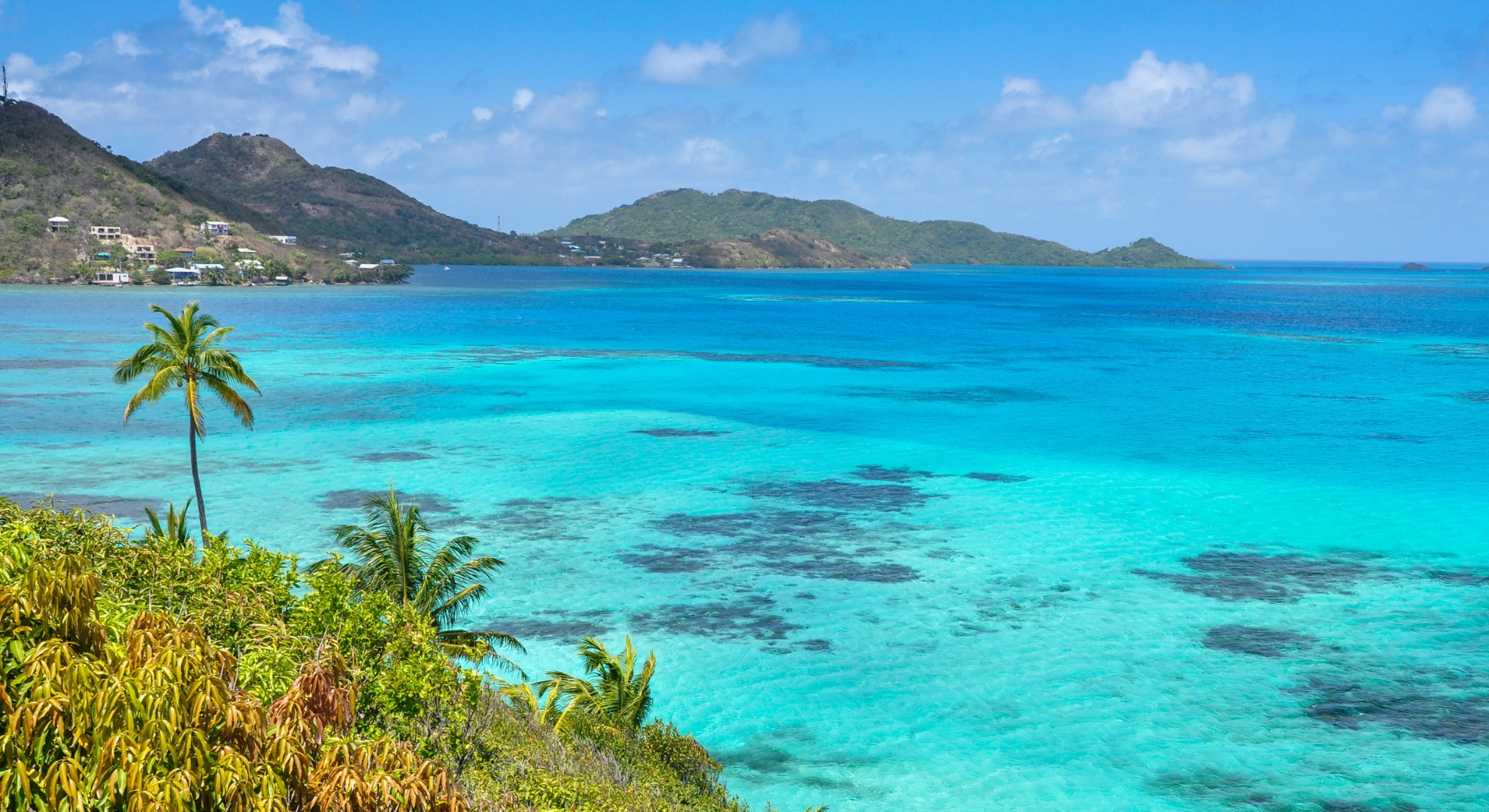 Turquoise ocean waters framed by lush green hills, showcasing the natural beauty of Colombia's coastline.