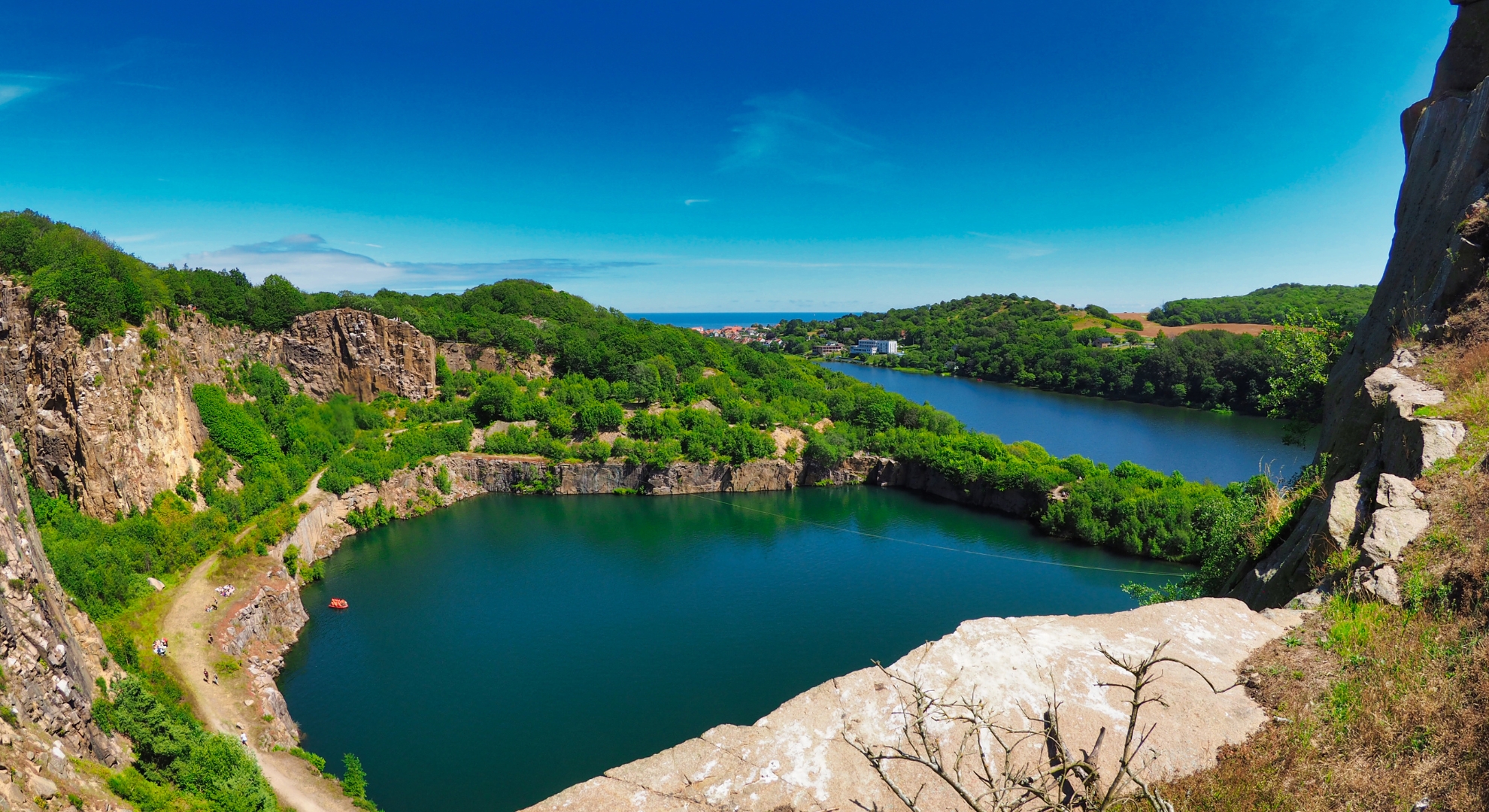 A scenic view of a Danish lake from the top of a cliff, showcasing the tranquil water and surrounding landscape.