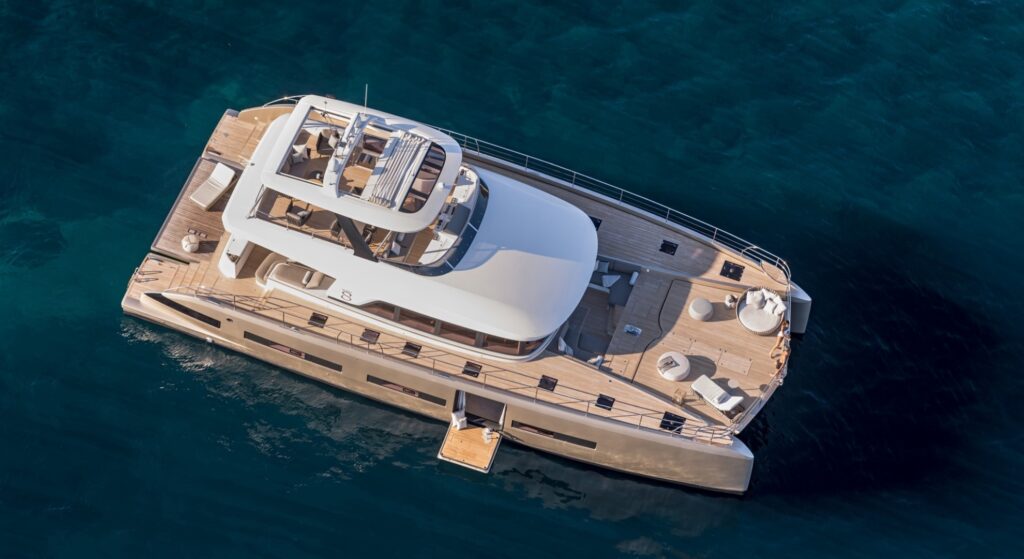 Luxury catamaran yacht with spacious deck cruising in clear blue waters.
