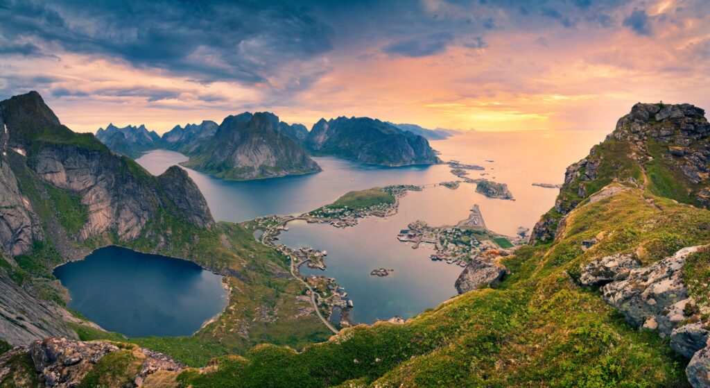 Scenic view of the Lofoten Islands in Norway, showcasing dramatic peaks and serene waters under a clear blue sky.