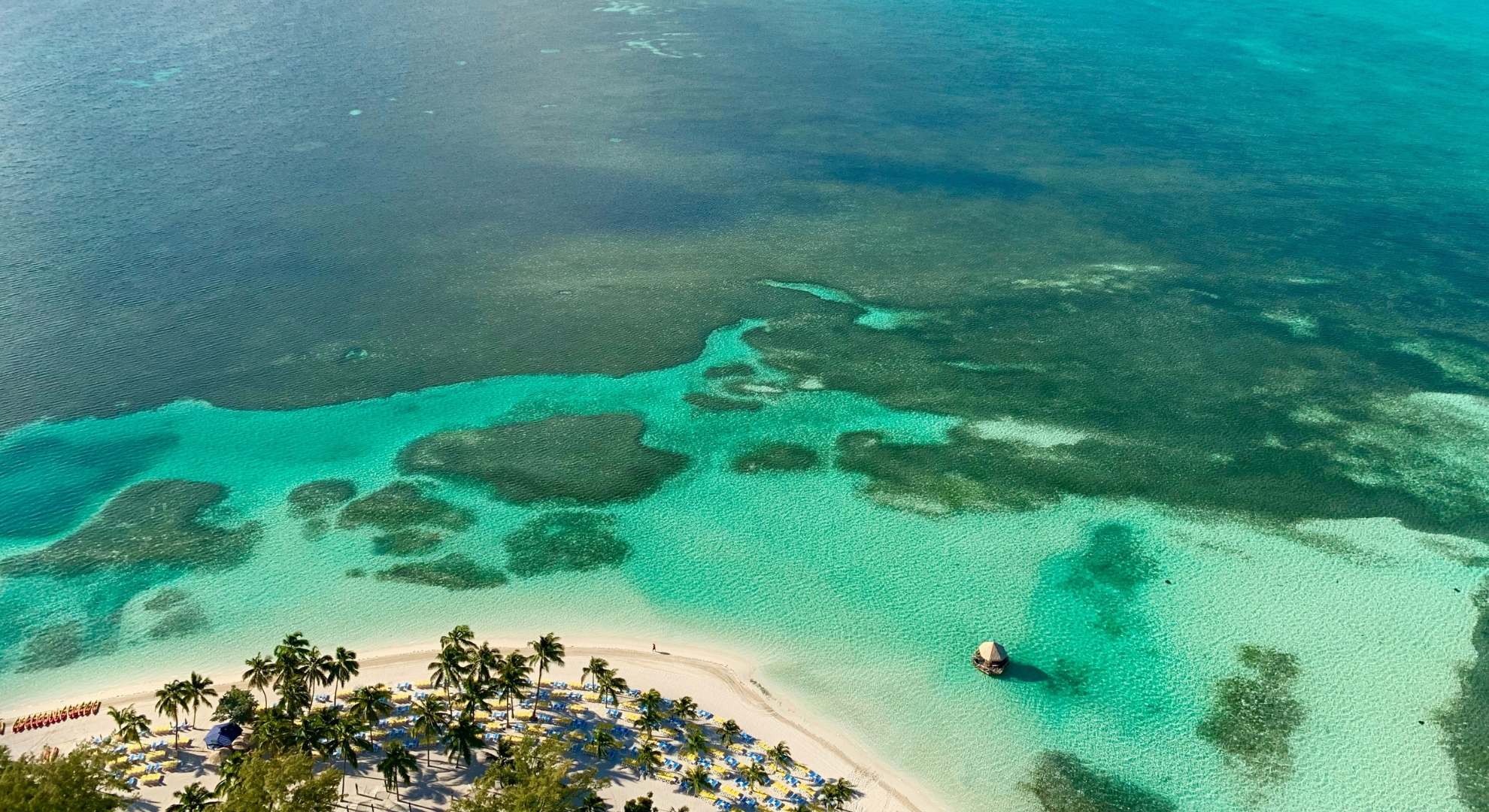 Scenic aerial view of a beach in the West Caribbean, featuring sparkling turquoise water and golden sand.