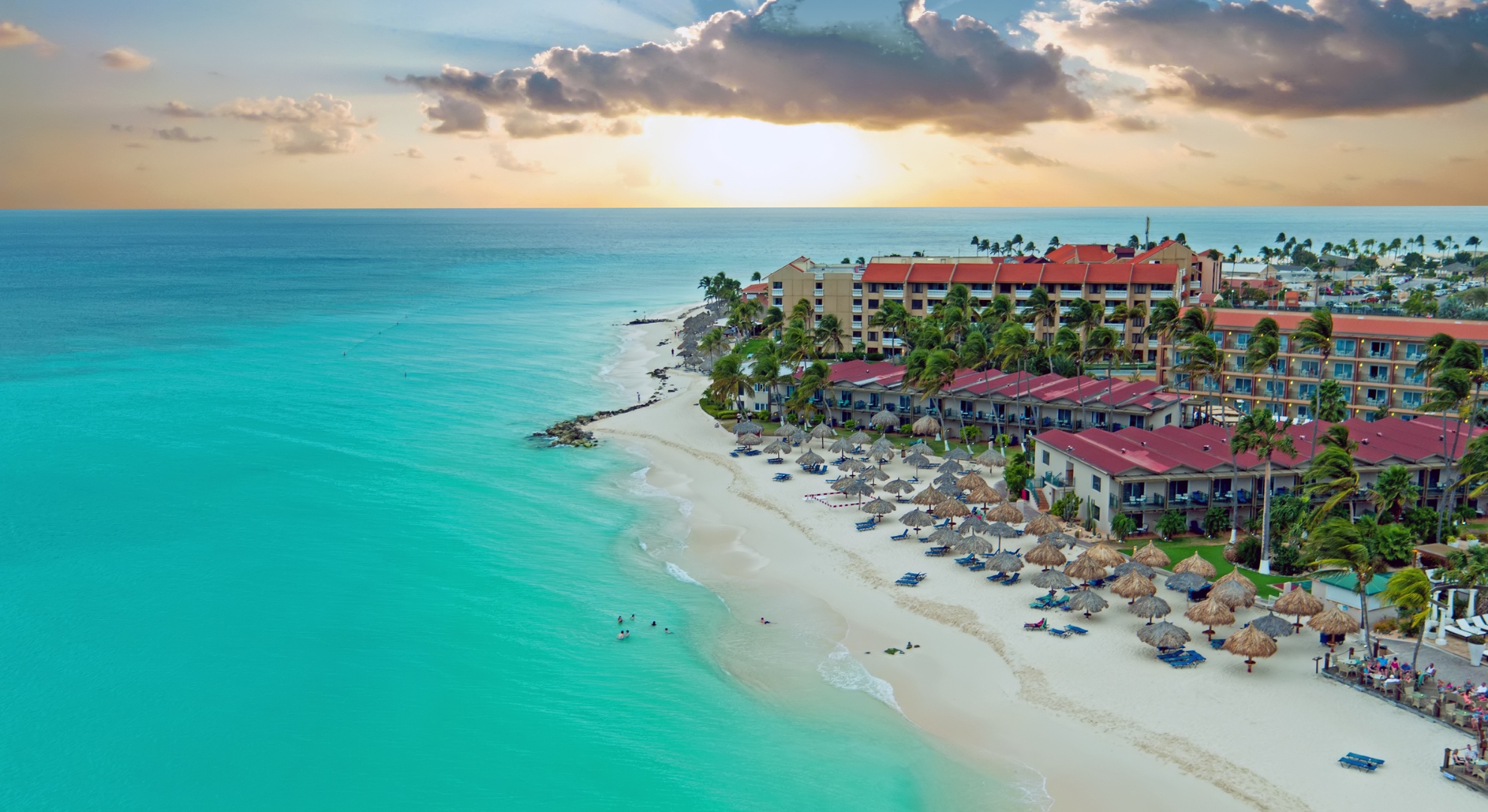 Sunset over a beach with a resort and hotel, showcasing the tranquil beauty of the ABC Islands.