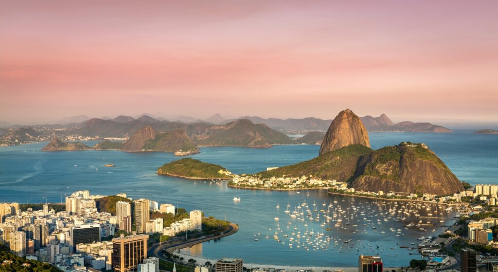 A stunning sunset view of Sugarloaf Mountain in Rio de Janeiro, Brazil, with warm hues illuminating the landscape.