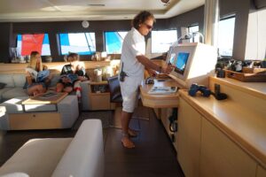 A man works on a computer aboard the super yacht S/Y KASKAZI FOUR, surrounded by water and luxury.