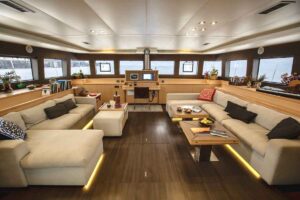 The living room interior of S/Y KASKAZI FOUR, featuring luxurious decor and ample seating in a bright, open space.