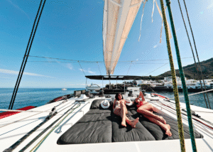 Two people relaxing on the deck of the super yacht S/Y KASKAZI FOUR under a clear blue sky.