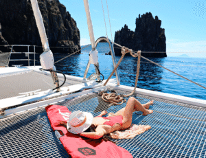 A woman relaxing on the deck of the super yacht S/Y KASKAZI FOUR, enjoying the sun and sea views.