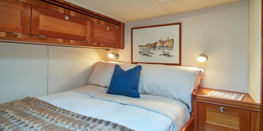 A cozy bedroom on the DARK STAR OF LONDON yacht featuring a bed and a wooden cabinet.