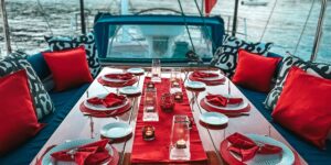 A dinner table elegantly set on the DARK STAR OF LONDON yacht, featuring fine dining ware and a scenic water view.