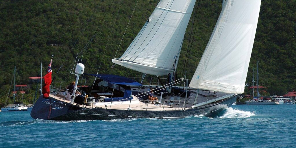 The DARK STAR OF LONDON yacht with white sails sailing smoothly on the ocean.
