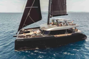 The SUNREEF 80 NALANI catamaran gliding through the ocean waves on a sunny day.
